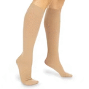 Nude knee-high compression stockings on a person’s legs for circulation support and varicose vein relief.